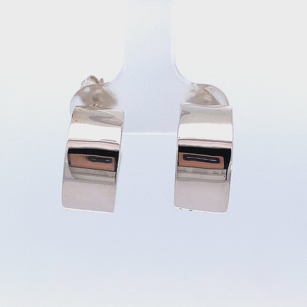 video of a pair of silver wide hoop earrings on a white background