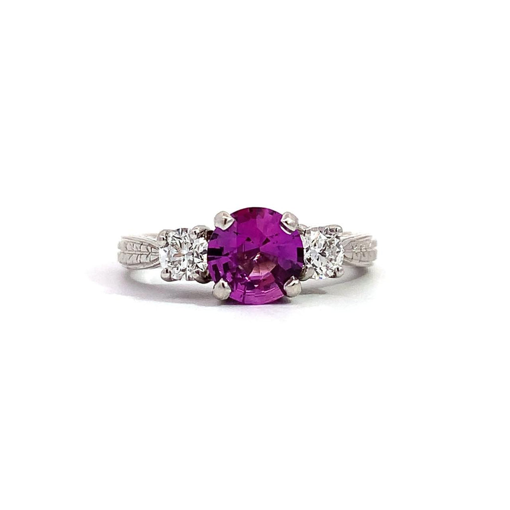 photo of a white gold 3 stone ring center pink sapphire and outer diamonds on a white background