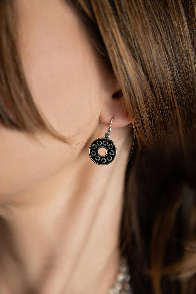 photo of a brunette model wearing a silver and black circle drop style earring