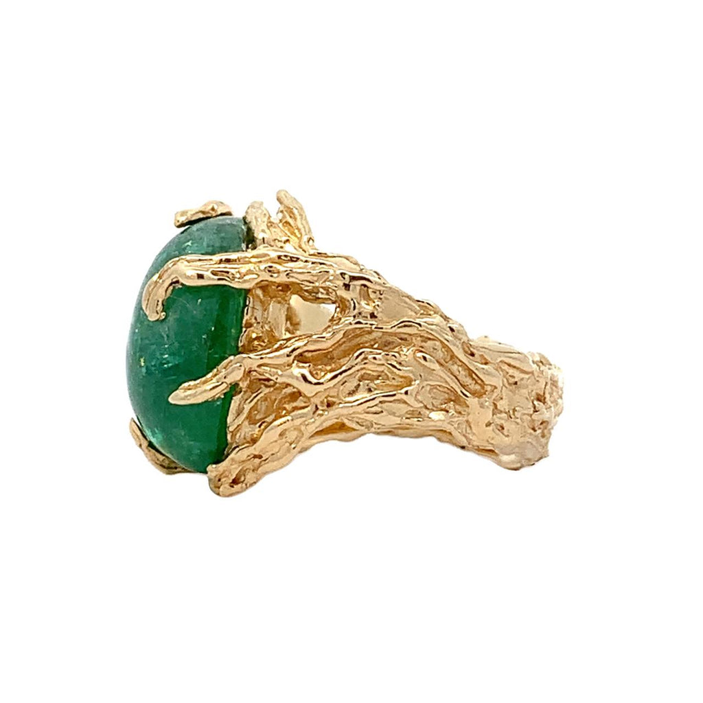 photo of a rough textured yellow gold ring with a green gem on a white background side view 