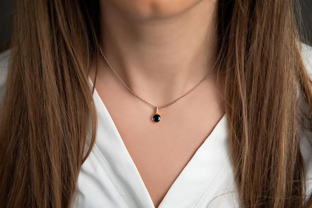 photo of abrunette model wearing a rose gold pendant necklace with a bezel set round black spinel
