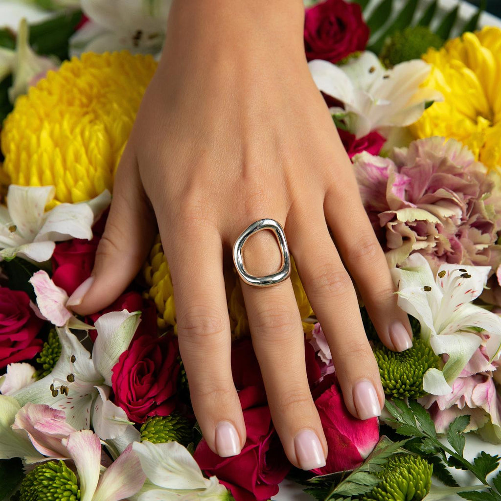 models hand on flowers wearing a modern silver ring