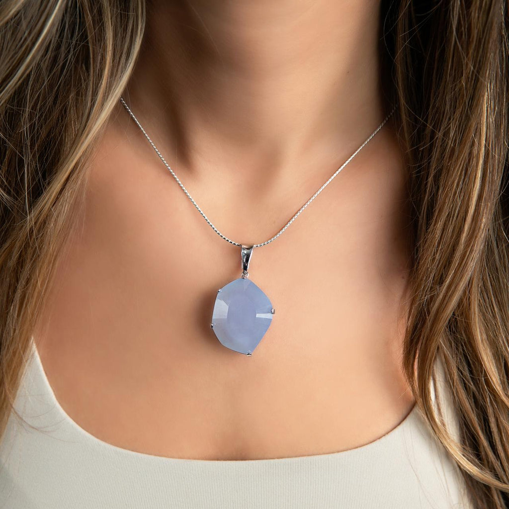 photo of a brunette model wearing a silver pendant necklace with a modern cut blue chalcedony 