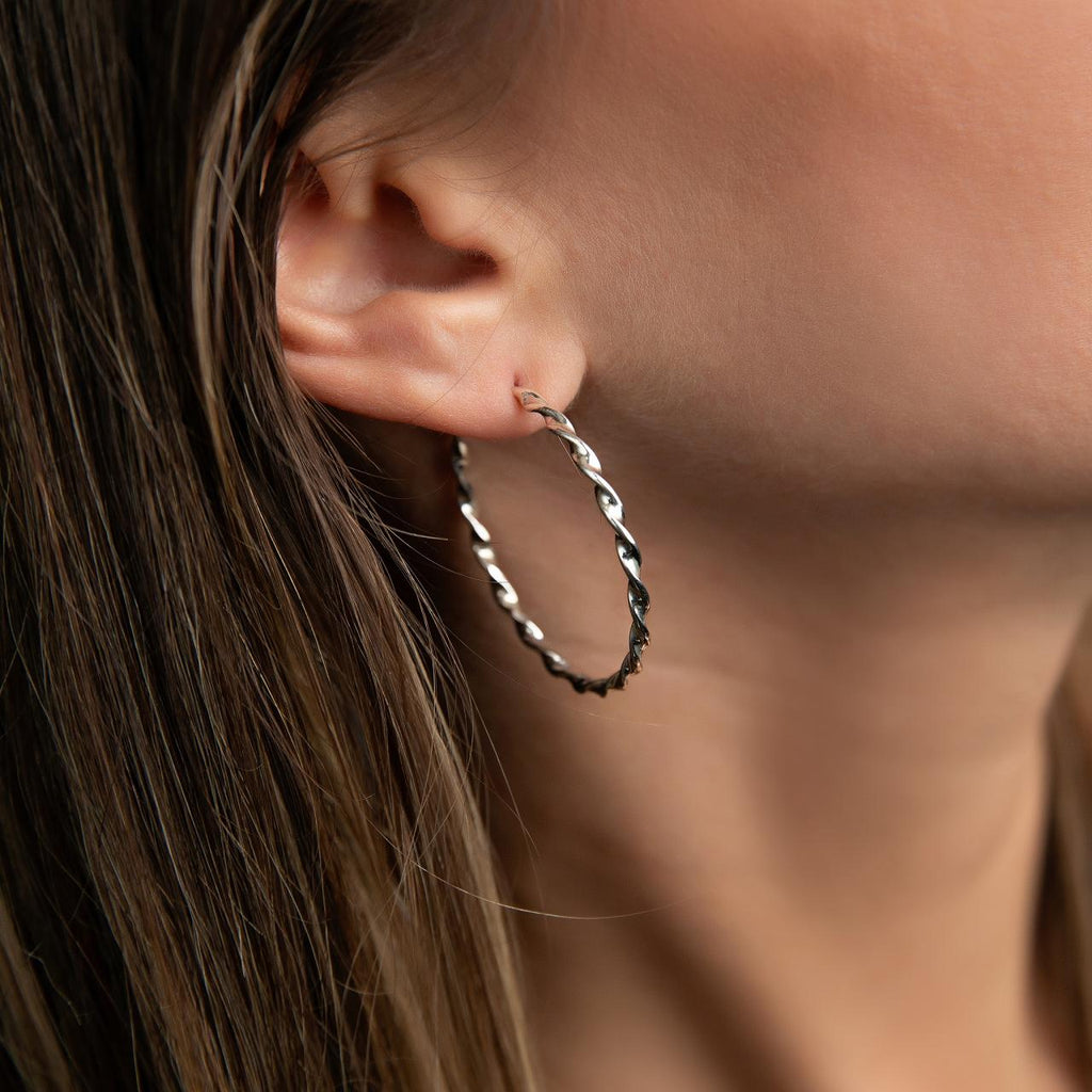 photo of a model wearing a twisted silver hoop earring