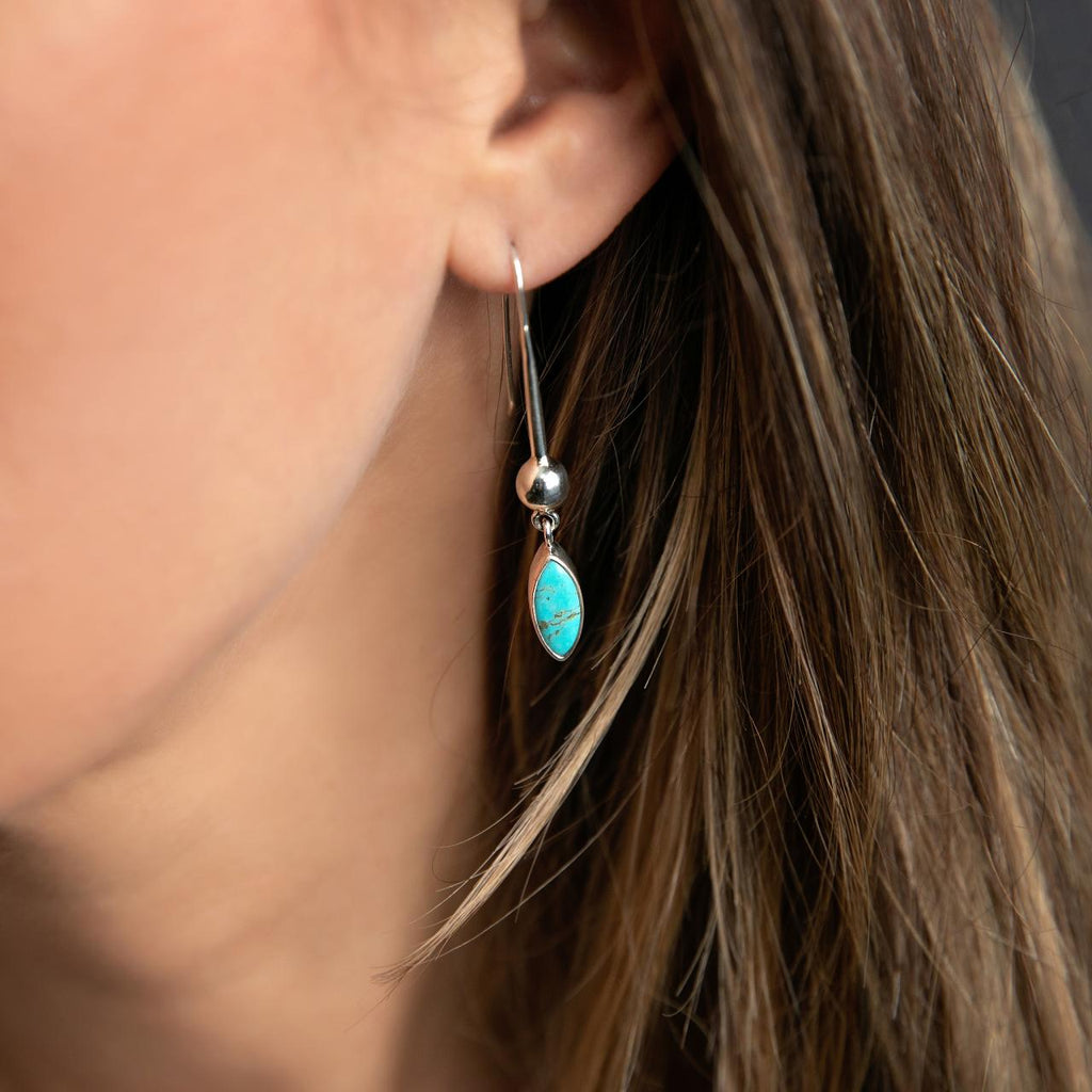 photo of a silver drop earring with a marquise shaped turquoise on a brunette model 